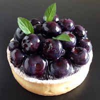 a blueberry tart with mint leaves on top